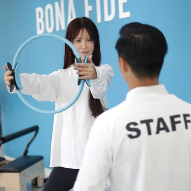 トレーナーがピラティスリングを使った種目を会員に提案する様子